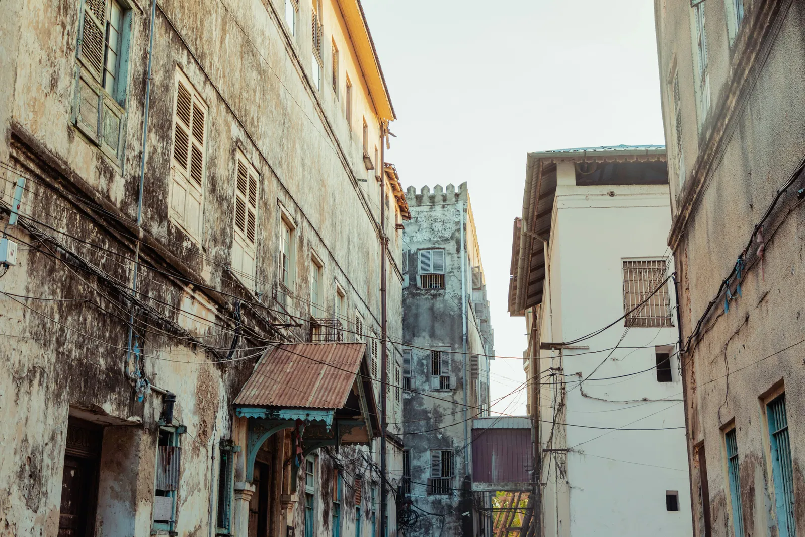 A narrow Stone Town lane opening toward a clock tower