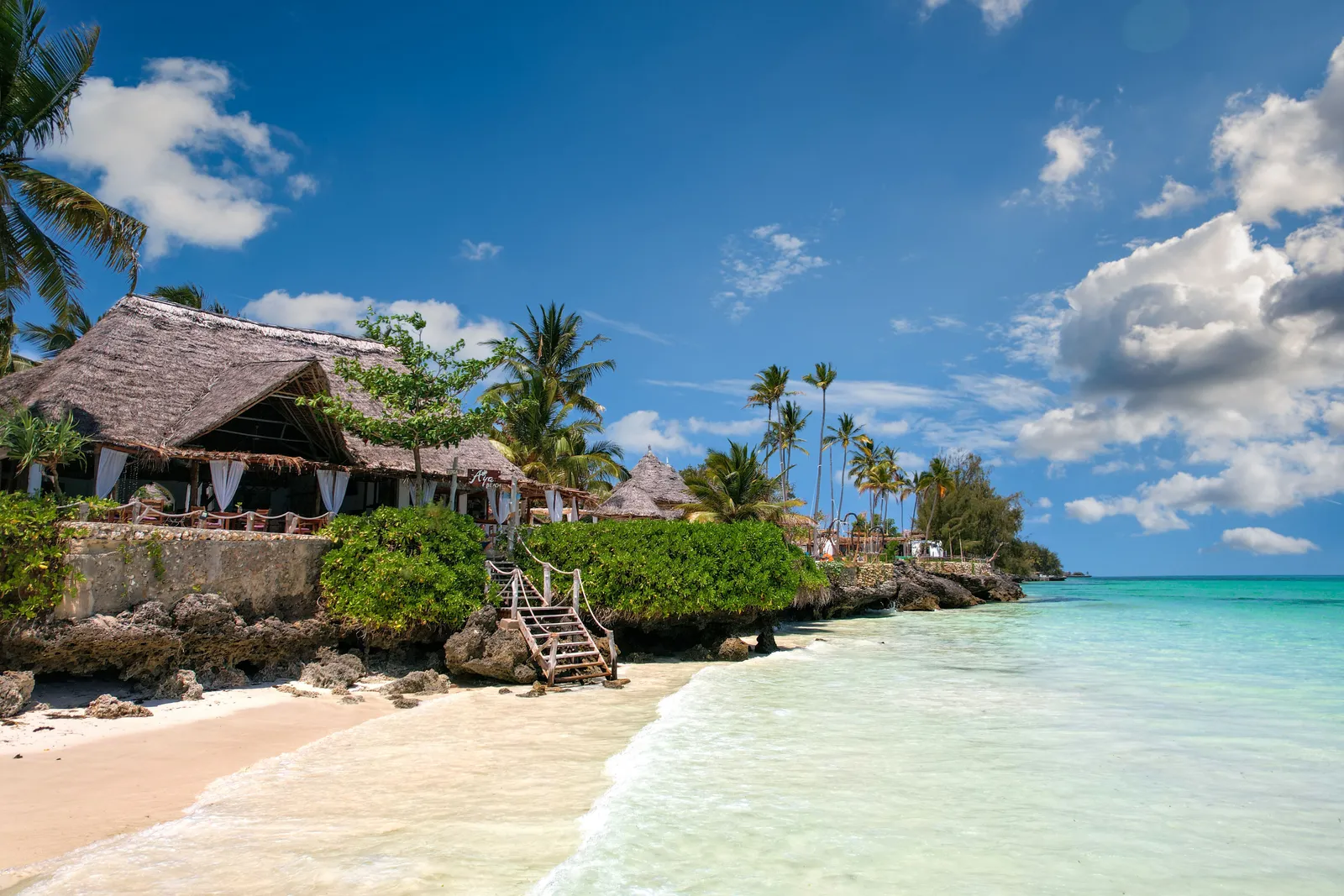 Palm trees and a villa over a quiet Zanzibar beach