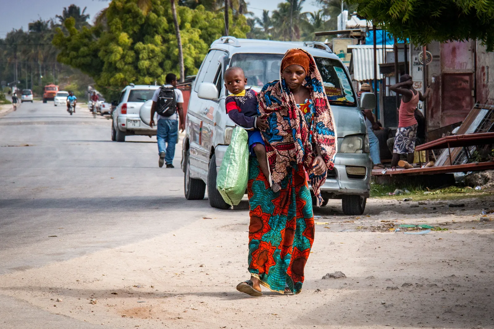 A mother and child walking through a bright Stone Town street