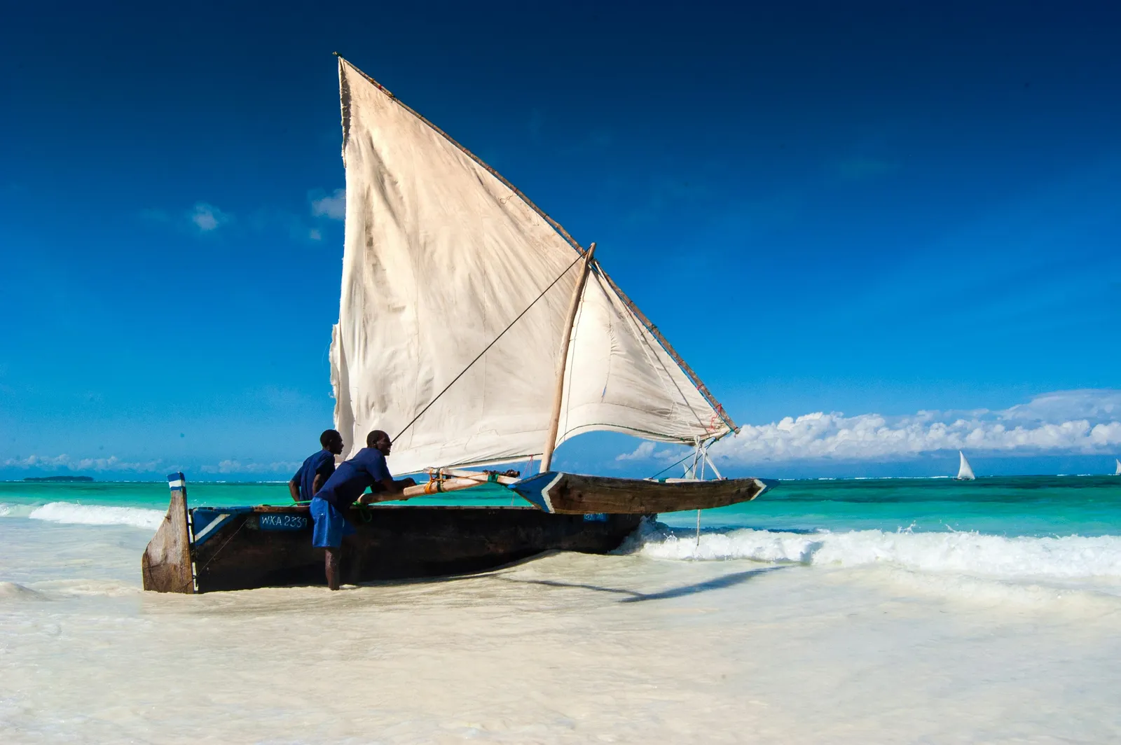 A fisherman sitting on a beached sailing dhow at Matemwe